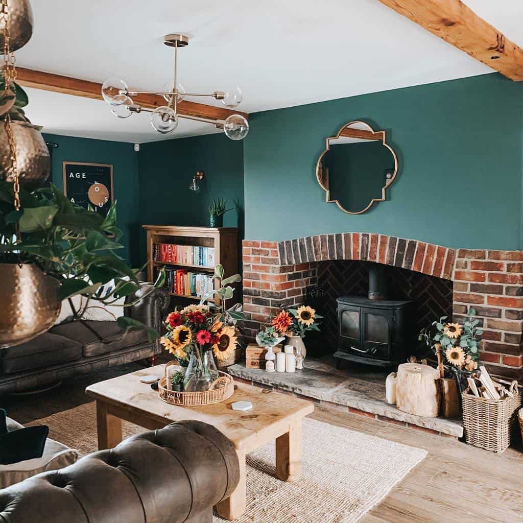 Cozy living room with a green wall, brick fireplace, sunflowers on a wooden coffee table, leather sofa, hanging plants, and bookshelf