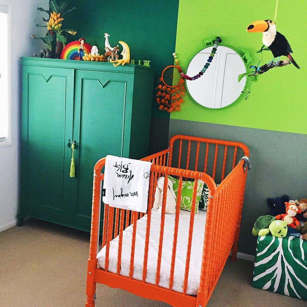 Vibrant nursery with an orange crib, green wardrobe, and jungle-themed decor, featuring a toucan plush and tropical accents