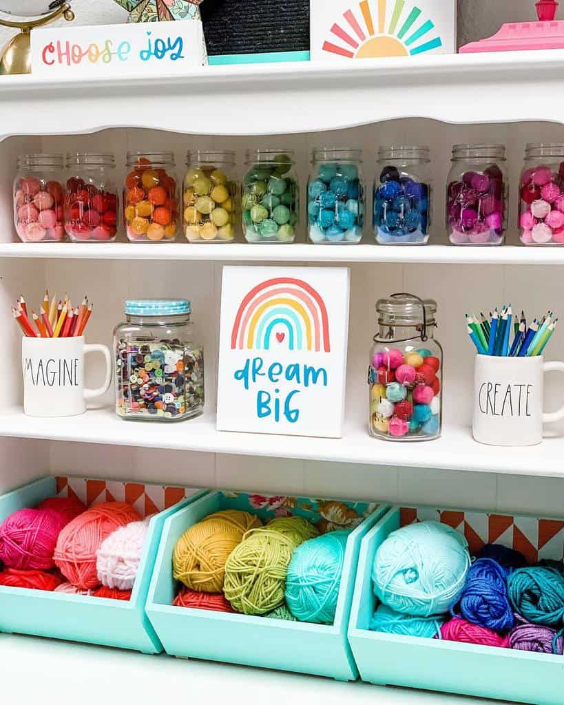 Colorful craft shelf with rainbow-themed wood signs reading 'Choose Joy' and 'Dream Big,' surrounded by jars of yarn and art supplies