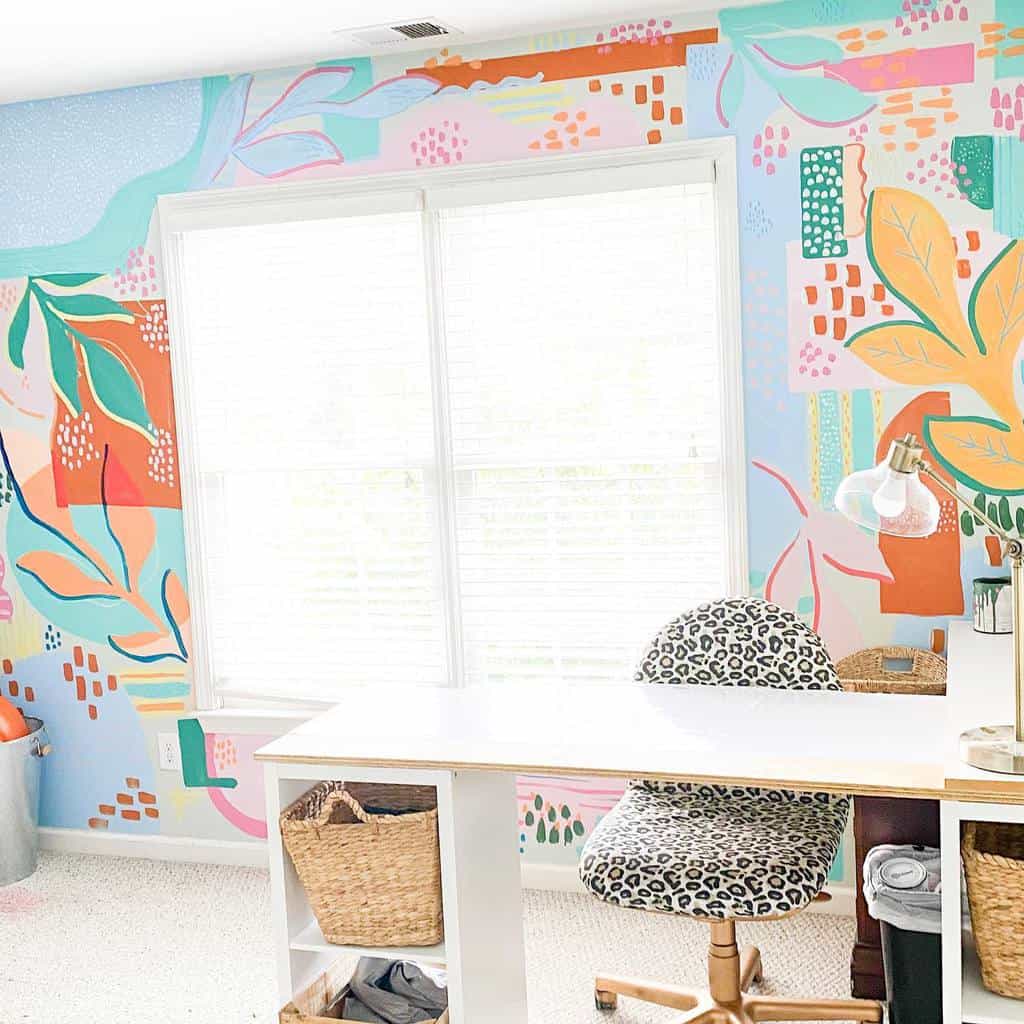 Bright home office with a colorful mural wall, white desk, leopard-print chair, and natural light from a window