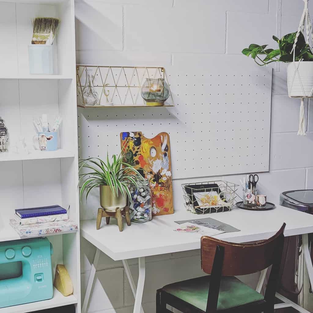 Bright crafting nook with desk, chair, sewing machine, plants, art supplies, pegboard, and shelves; a creative and organized space