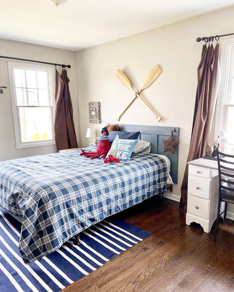 Nautical-themed bedroom with a blue plaid bedspread, wooden oars as wall decor, and coastal accents, creating a cozy lakeside retreat