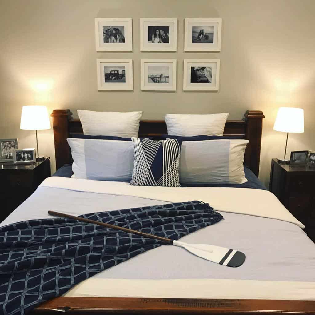 Cozy bedroom with a neatly made bed, decorative pillows, a blue patterned blanket, a paddle across the bed, and framed photos on the wall