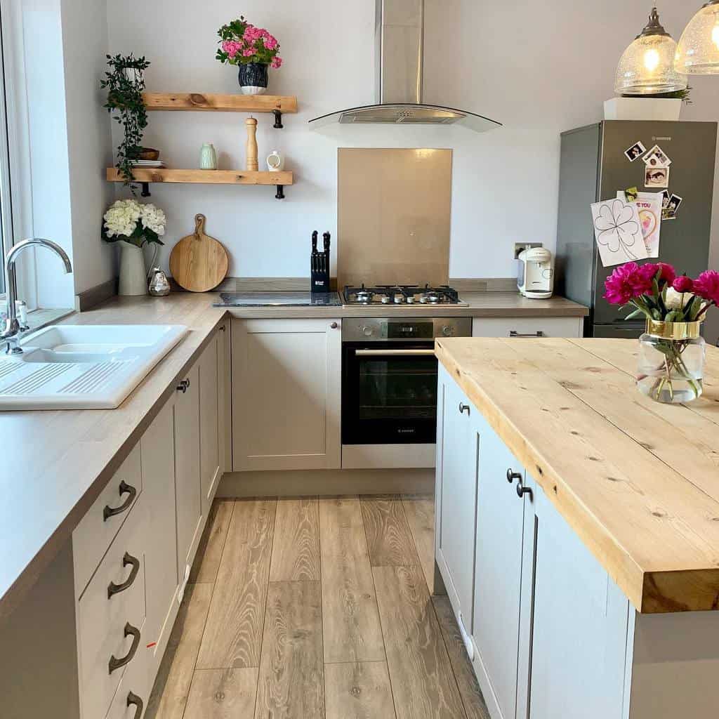 Wooden kitchen shelves with black brackets hold plants, ceramics, and decor, adding warmth and charm to a modern farmhouse space