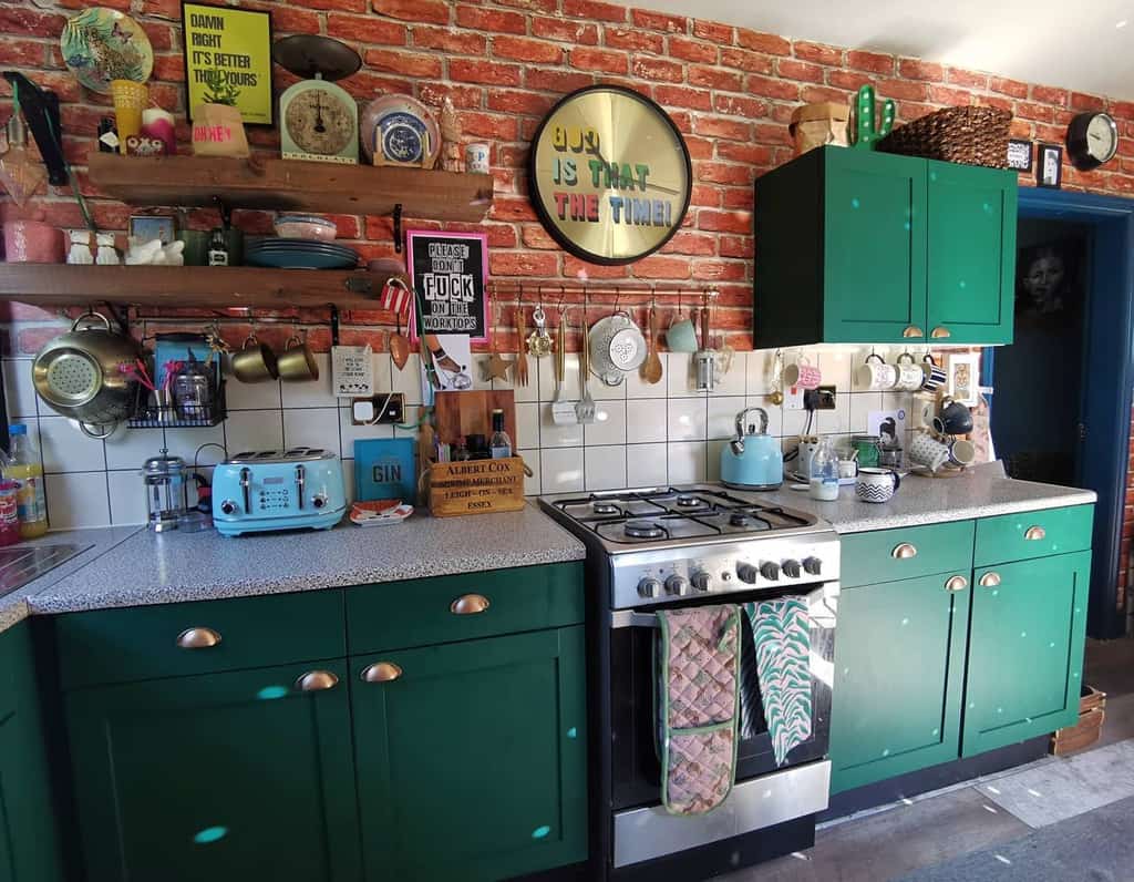 Rustic wooden shelves on a brick wall hold colorful mugs, dishes, and vintage decor, adding eclectic charm to a retro-inspired kitchen