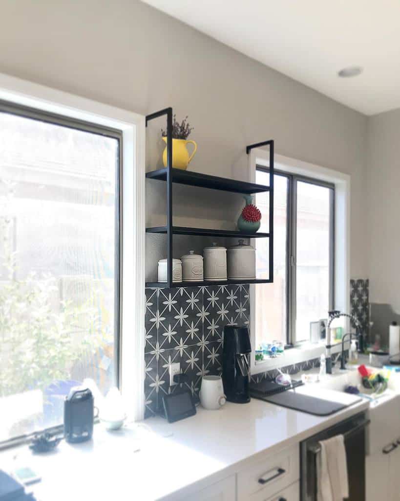 Bright kitchen with star-patterned backsplash, sleek black open shelves, jars, a yellow pitcher, and a red decoration