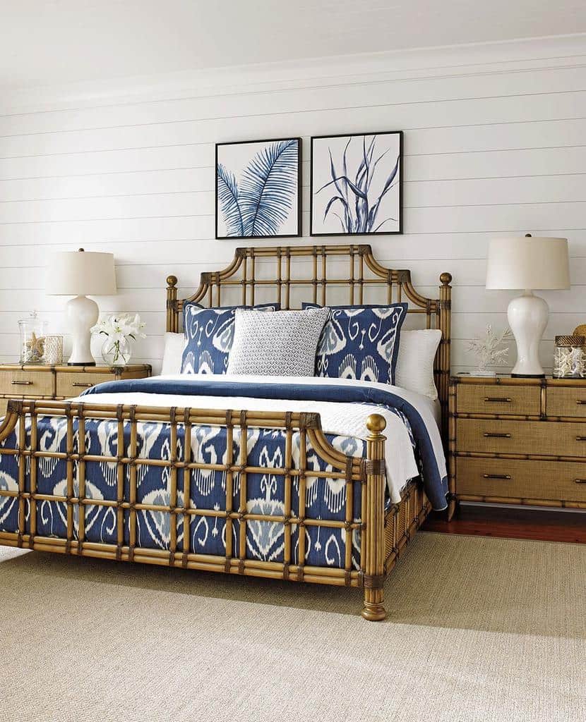 Bedroom with a bamboo bed frame, blue patterned bedding, two lamps on wooden nightstands, and two framed leaf prints on the wall