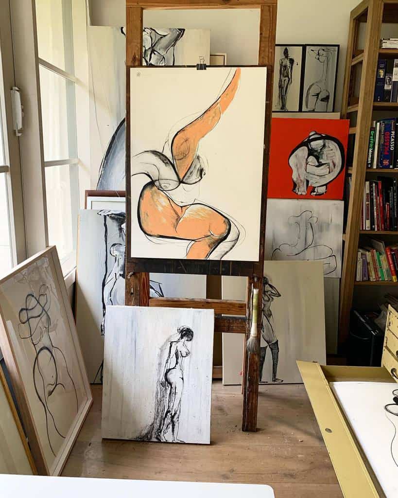 Art studio with multiple figure paintings on canvases, featuring dynamic poses and abstract styles in a variety of colors