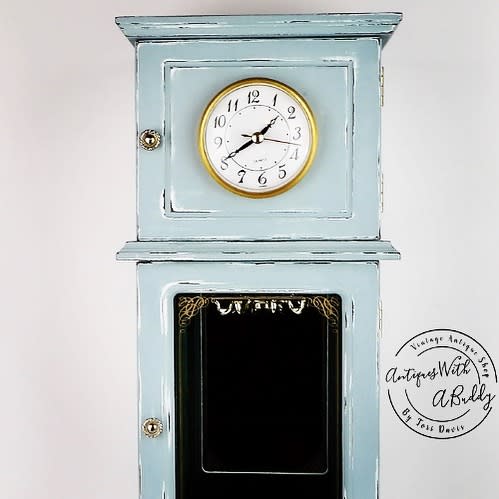 Vintage wall clock with a distressed light blue chalk paint finish, gold accents, and glass detailing, set against a white background