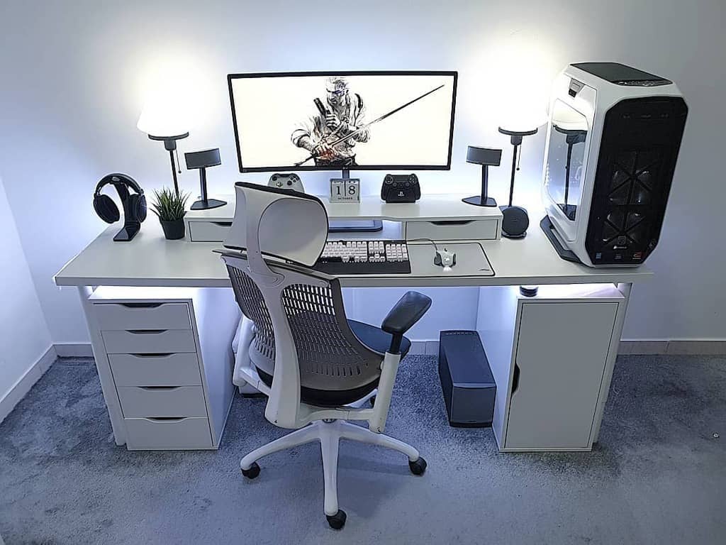 Sleek computer setup with a widescreen monitor, white desk, gaming chair, keyboard, mouse, and PC tower; minimalist and modern design