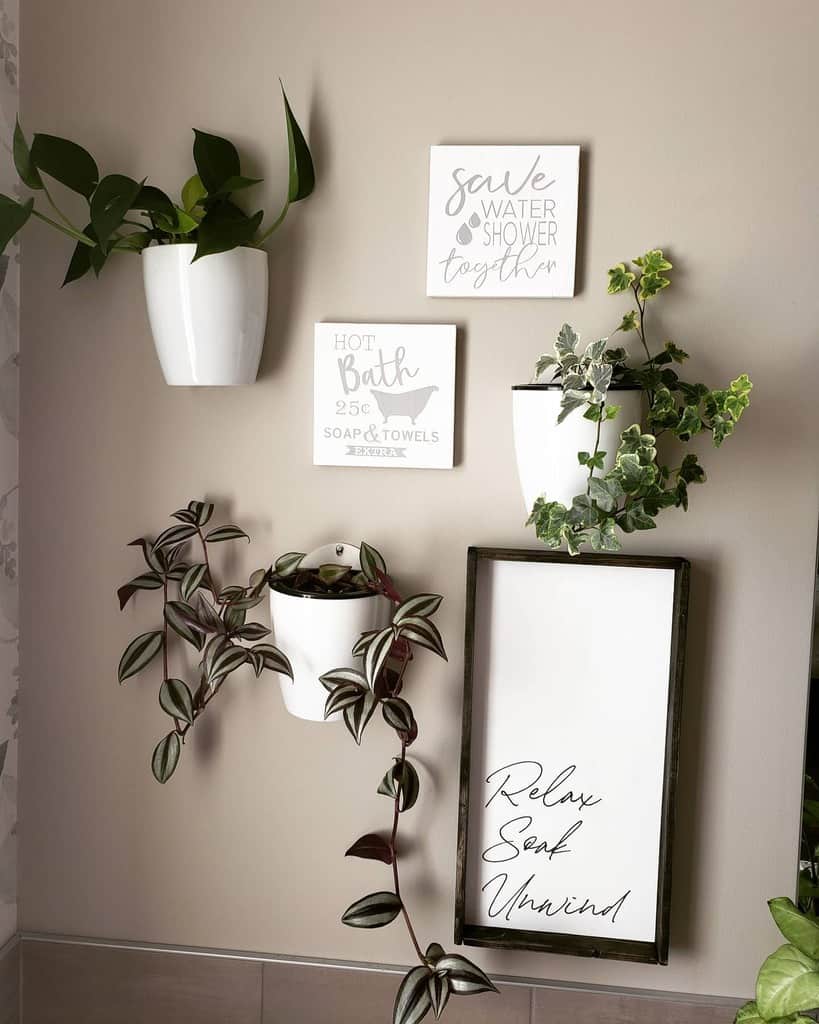 Bathroom wall with farmhouse-style wood signs reading 'Relax, Soak, Unwind' and 'Save Water, Shower Together,' accented by hanging plants