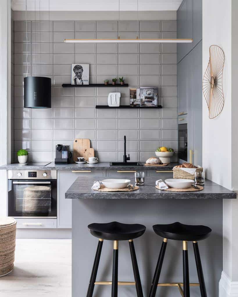 Sleek black floating shelves on a gray tiled wall hold small plants, decor, and art, adding a modern touch to this sophisticated kitchen