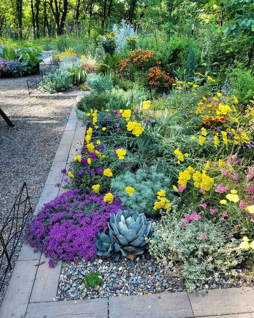 Colorful xeriscape garden with drought-tolerant flowers, succulents, and gravel pathways in a lush natural setting