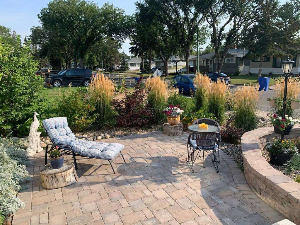 Cozy front yard patio with pavers, drought-tolerant grasses, flowering plants, and outdoor seating in a suburban setting