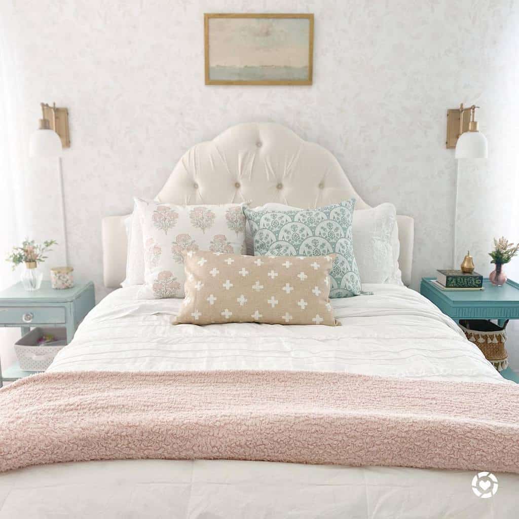 Elegant coastal bedroom with a tufted headboard, pastel accent pillows, and vintage blue nightstands, creating a soft and serene retreat