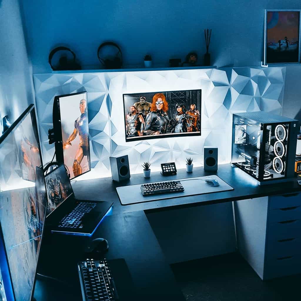 Futuristic gaming setup with multiple screens, RGB-lit PC, keyboard, and decorative wall panels, creating an immersive atmosphere