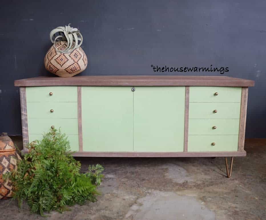 Mid-century modern sideboard with sage green chalk-painted drawers, a rustic wood frame, and brass hardware, styled with woven baskets