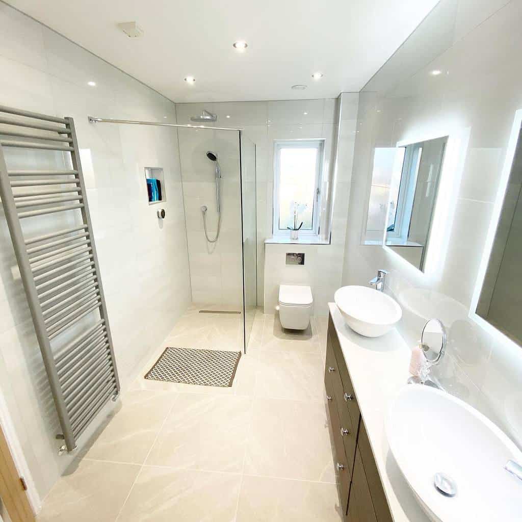 Modern wet room with a glass walk-in shower, sleek vanity dual sinks, wall-mounted toilet, and heated towel rack in neutral tones throughout