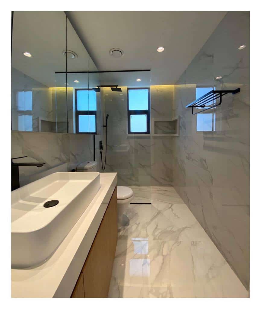 Minimalist wet room with marble walls, a floating vanity, black fixtures, and warm LED lighting for a sleek and modern look