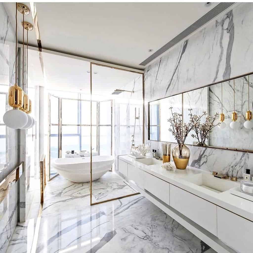 Luxurious wet room with marble walls, gold accents, a freestanding tub, and modern pendant lighting for an elegant spa-like feel