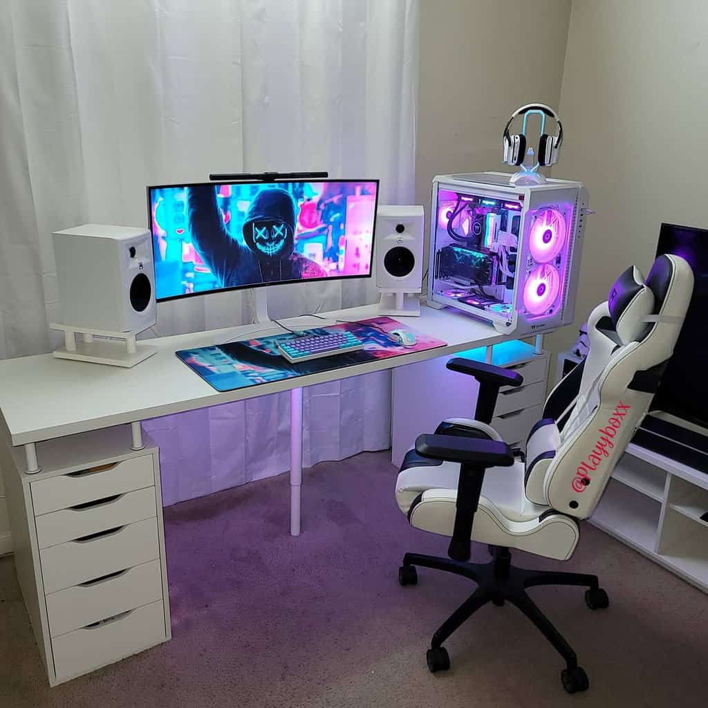 A modern gaming setup with a curved monitor, white speakers, RGB-lit PC, and white gaming chair in a room with white curtains