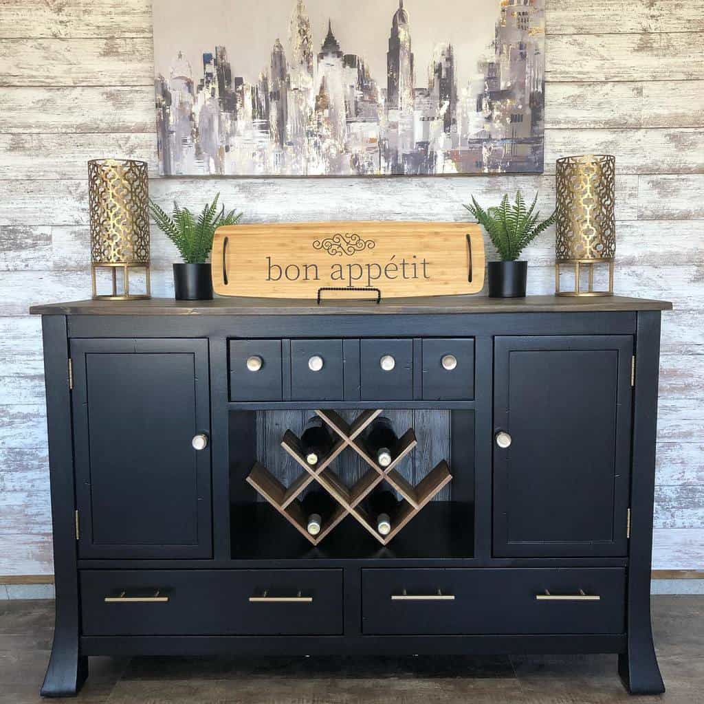 Matte black chalk-painted sideboard with a built-in wine rack, brass hardware, and rustic decor, styled against a weathered wood backdrop