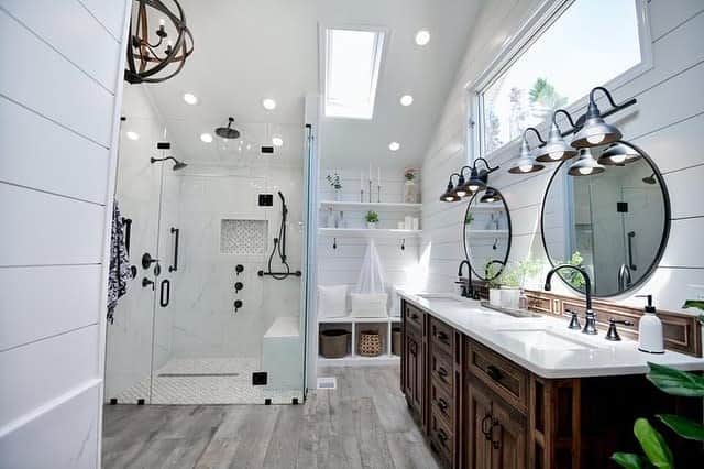 Rustic farmhouse wet room with wood vanities, black fixtures, a glass-enclosed shower, and shiplap walls for a cozy yet modern feel