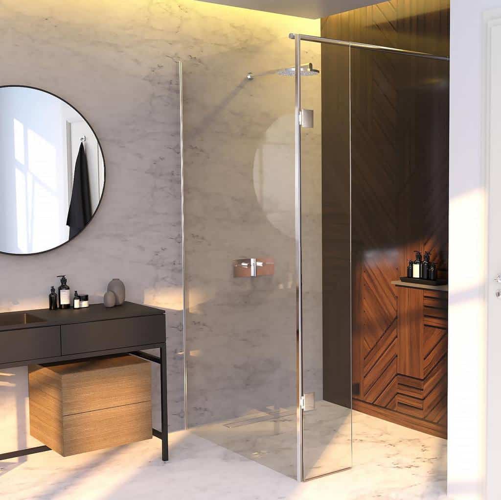 Modern wet room with a glass shower, marble walls, wooden cabinet, round mirror, and sunlight streaming through a window