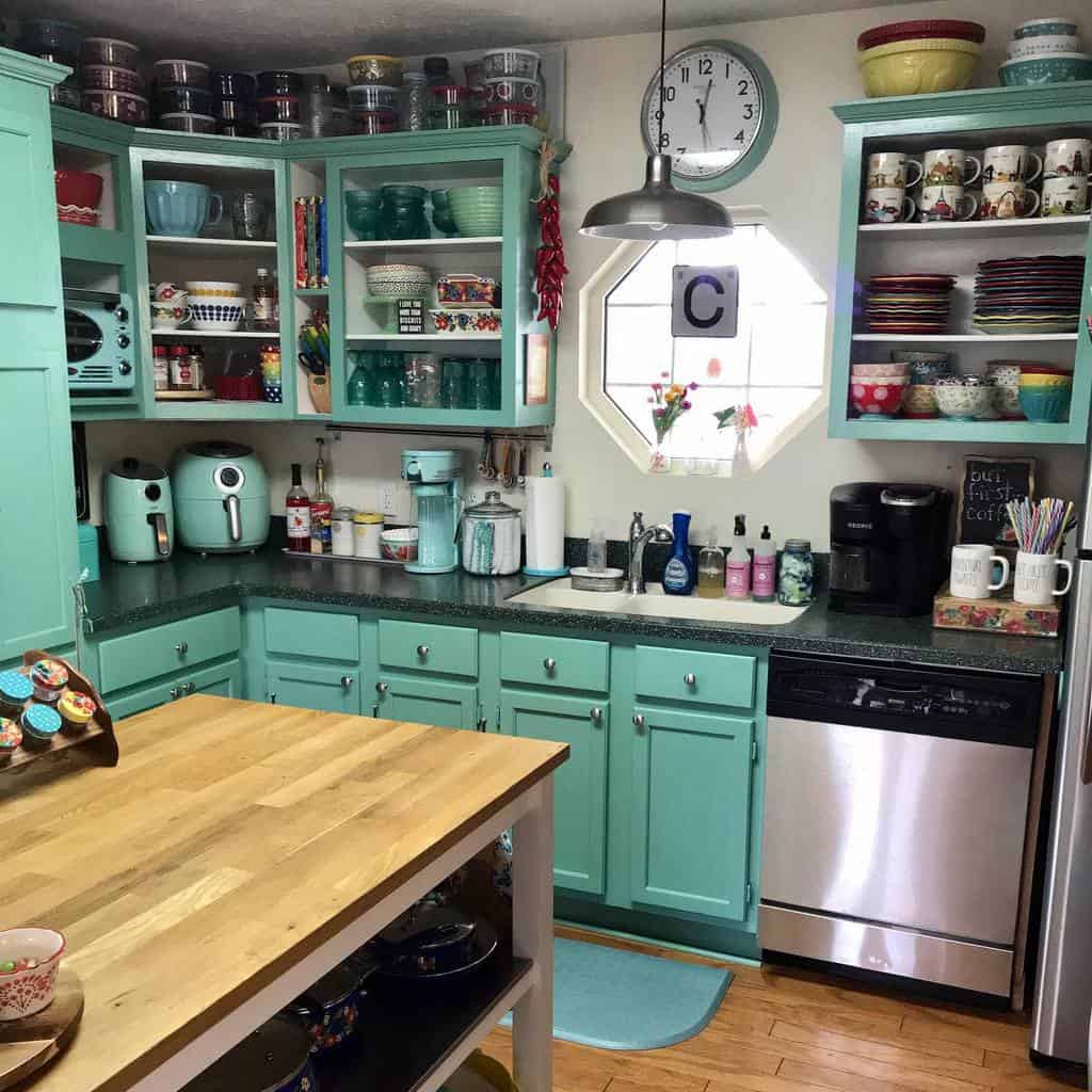 Cozy kitchen with turquoise cabinets, stainless steel appliances, wooden island, colorful dishes, and a clock on the wall