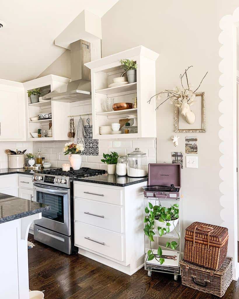 Bright kitchen with white cabinets, black countertops, plants, decorative items, and a vintage record player on a small stand