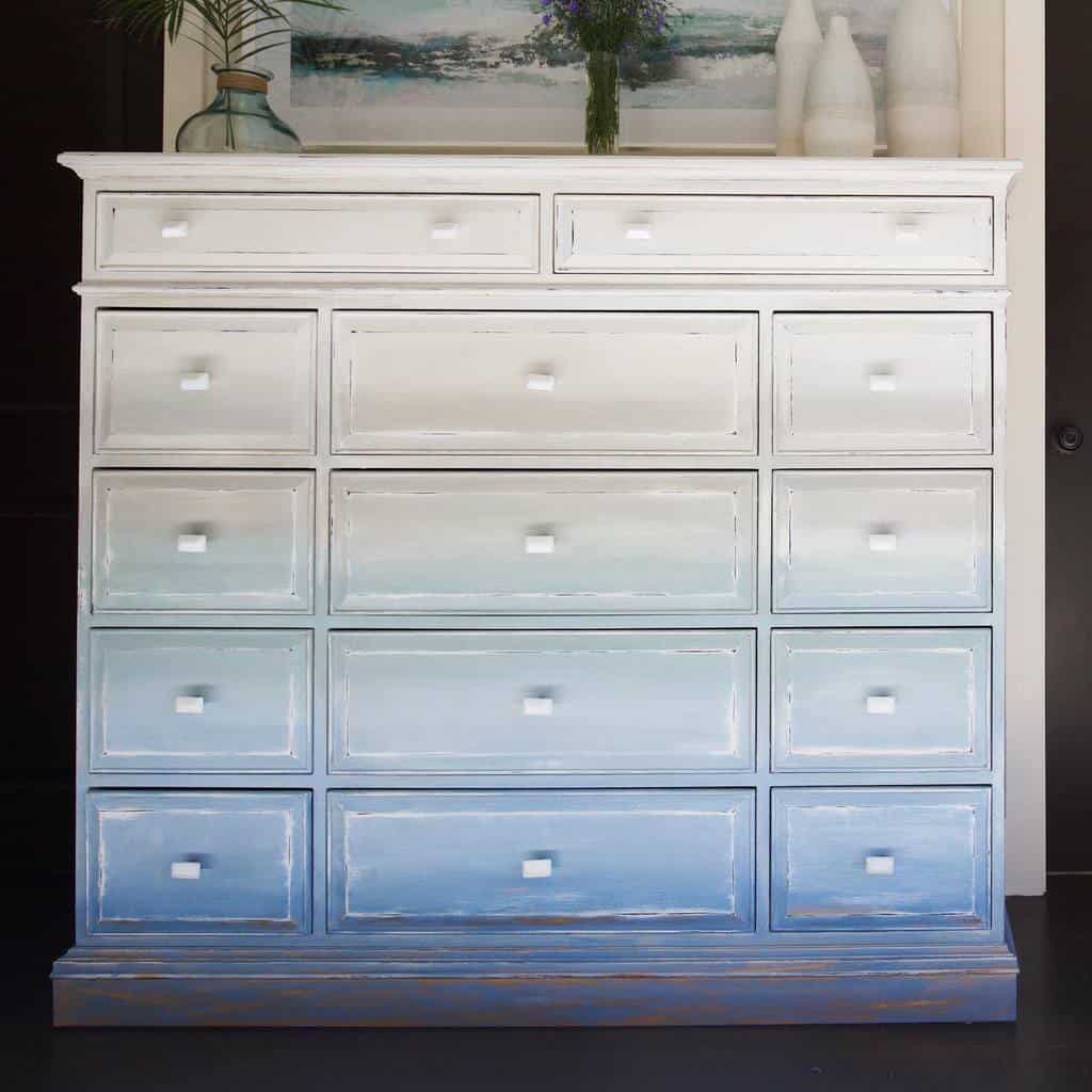 Large dresser with an ombre chalk-painted finish transitioning from white to blue, featuring distressed edges and square knobs