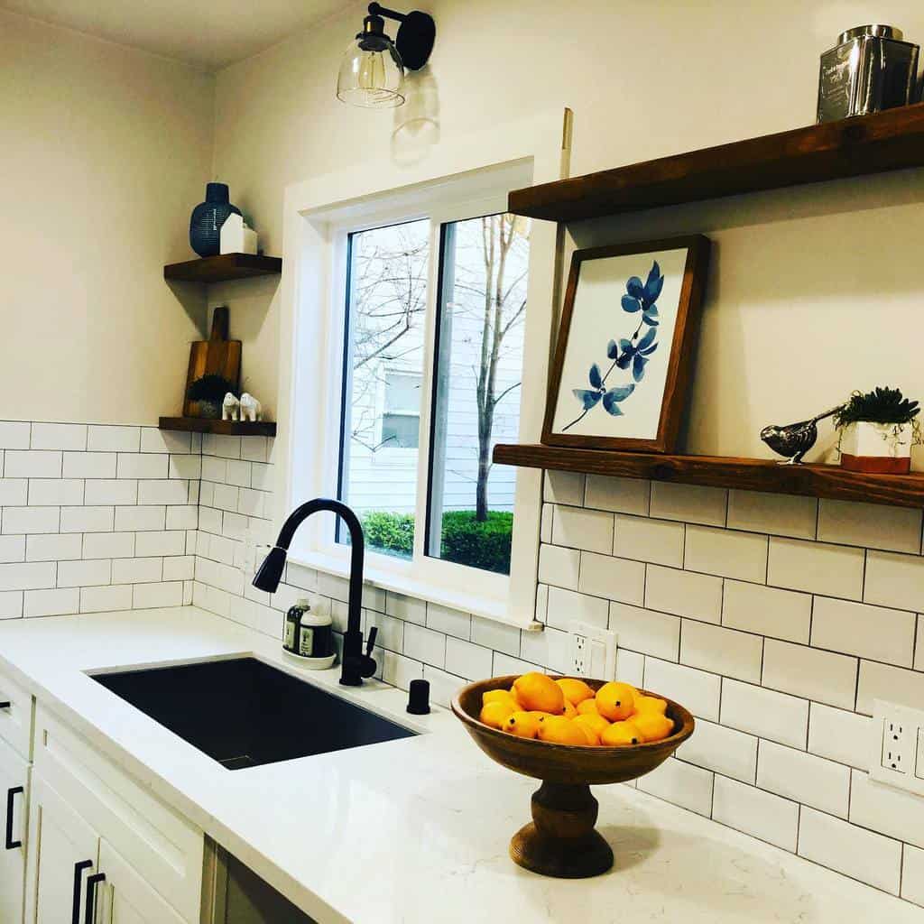 Rustic wooden floating shelves display framed art, decor, and plants, adding warmth to a modern farmhouse kitchen with white subway tiles