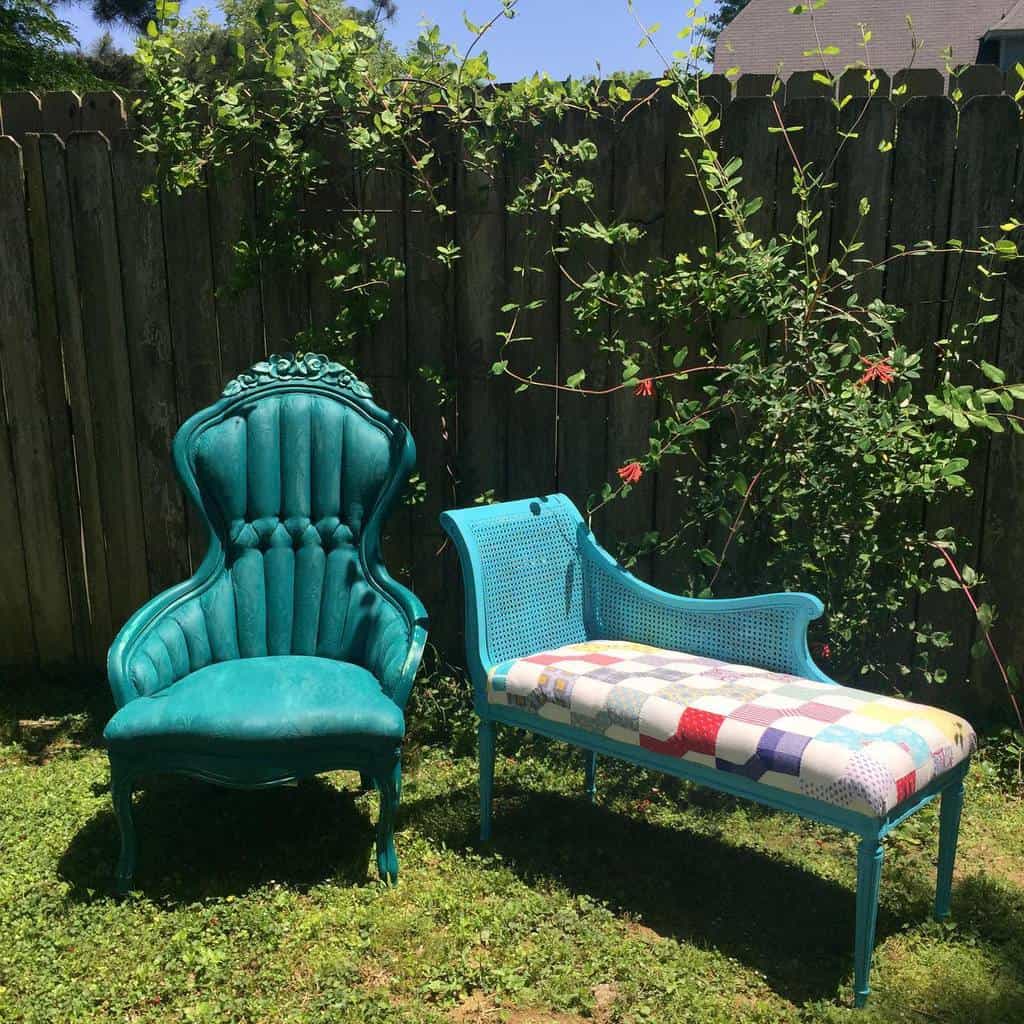 Vibrant teal chalk-painted vintage chair and bench with tufted fabric and cane detailing, set outdoors against a wooden fence with greenery