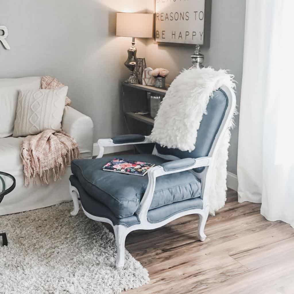 Vintage armchair with chalk-painted navy fabric and a white distressed frame, styled with a fluffy throw in a cozy living room