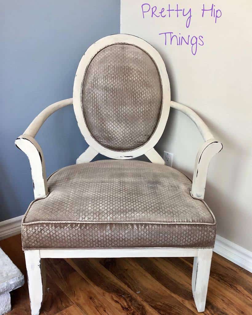 Vintage armchair with chalk-painted distressed white frame and textured beige fabric, set against a two-tone wall with handwritten text