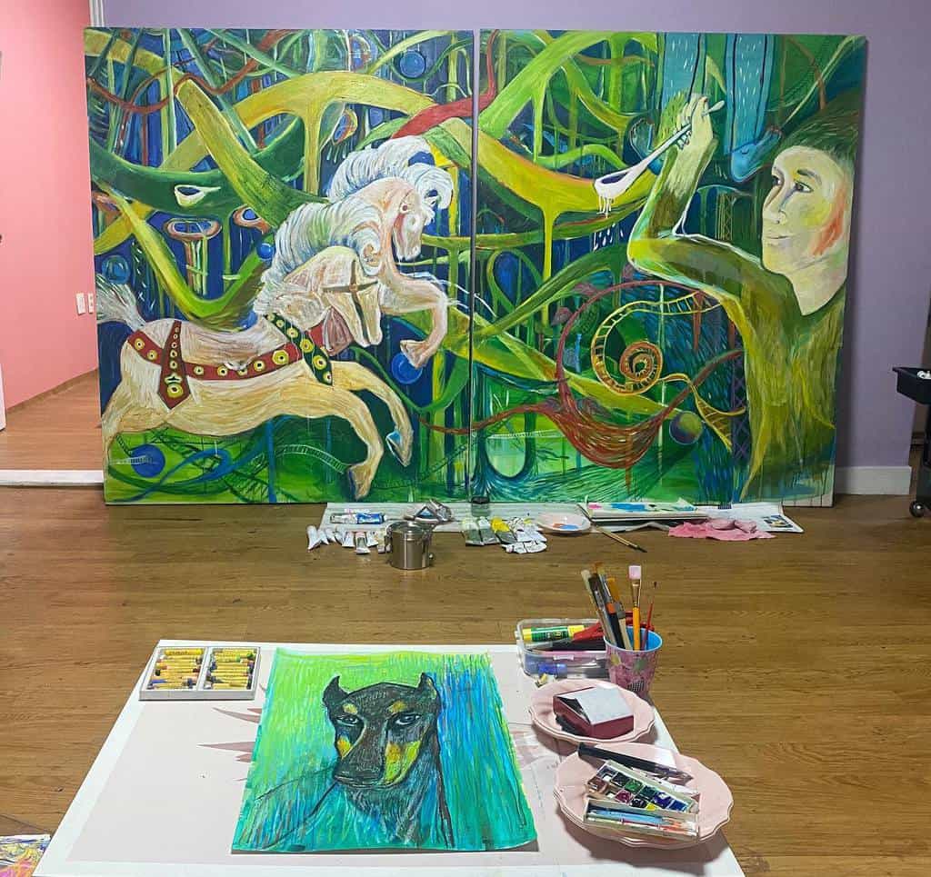 Art studio with colorful paintings: a carousel horse, playful abstract shapes, and a dog portrait on a table with art supplies