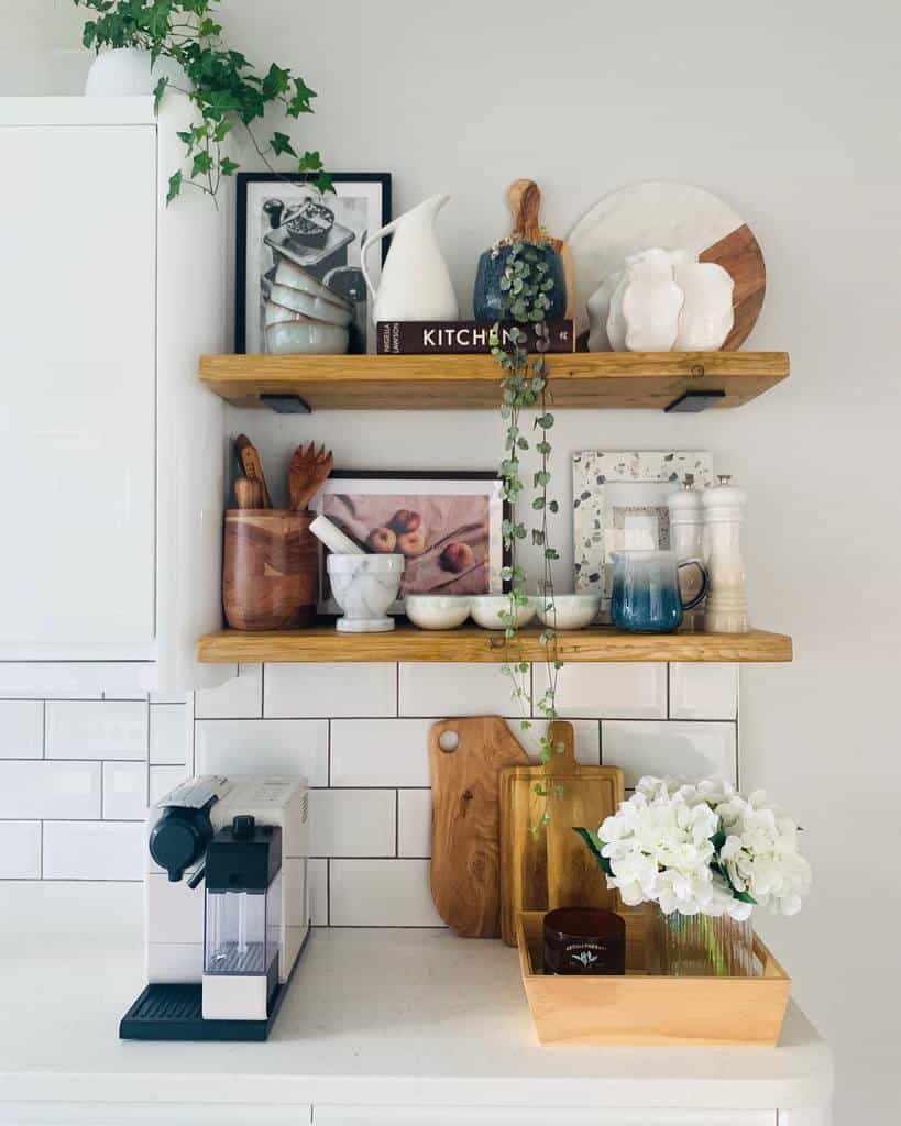 Kitchen shelves with cookbooks, decor, and plants; espresso machine on counter, white subway tiles, cutting boards, and a flower tray