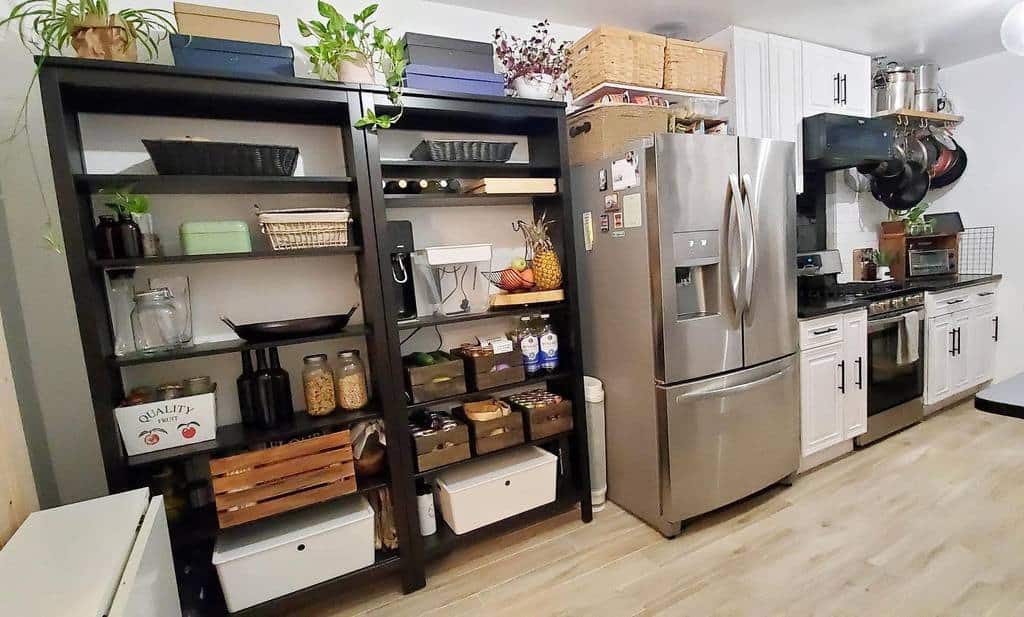 Black open pantry shelves store jars, baskets, and kitchen essentials, adding practical storage and rustic charm to a cozy farmhouse-style kitchen