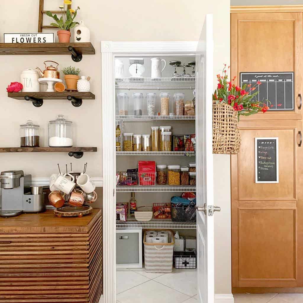 Organized kitchen pantry with jars and baskets, shelves with coffee station, and wooden cabinets with chalkboard panels