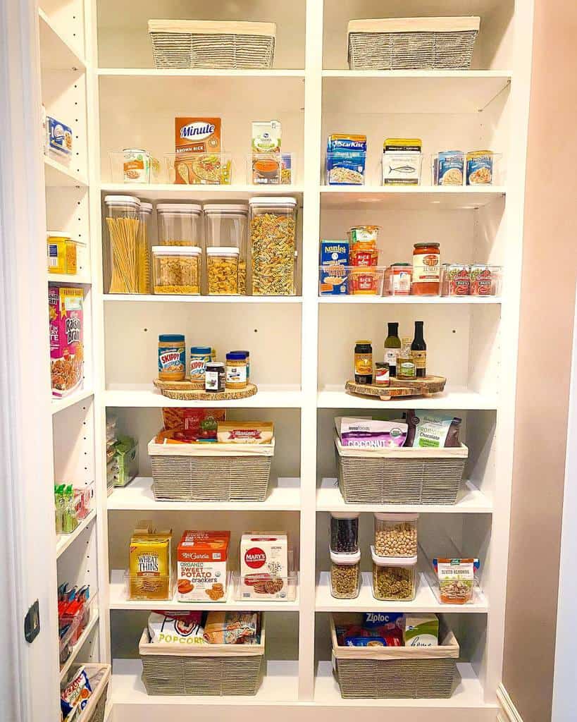 A neatly organized pantry with shelves of food items, baskets, jars of pasta, canned goods, and sauces