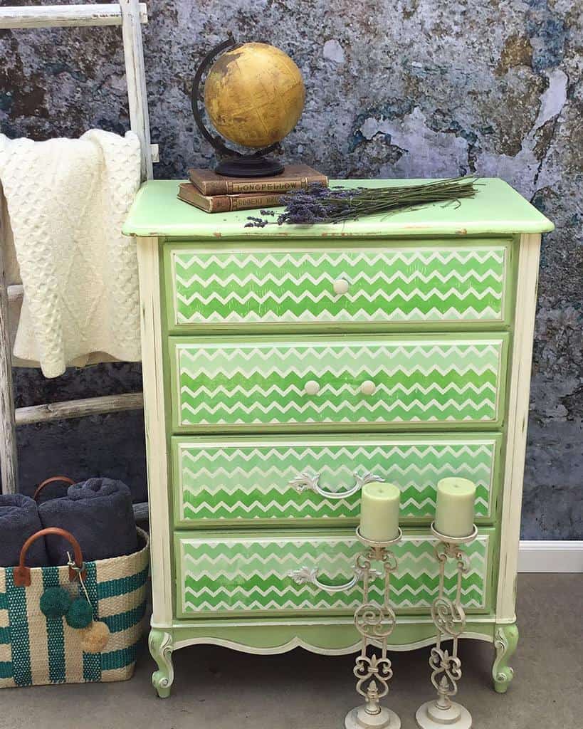 Vintage dresser with green and white chevron chalk-painted drawers, a distressed finish, and styled with rustic decor and a globe