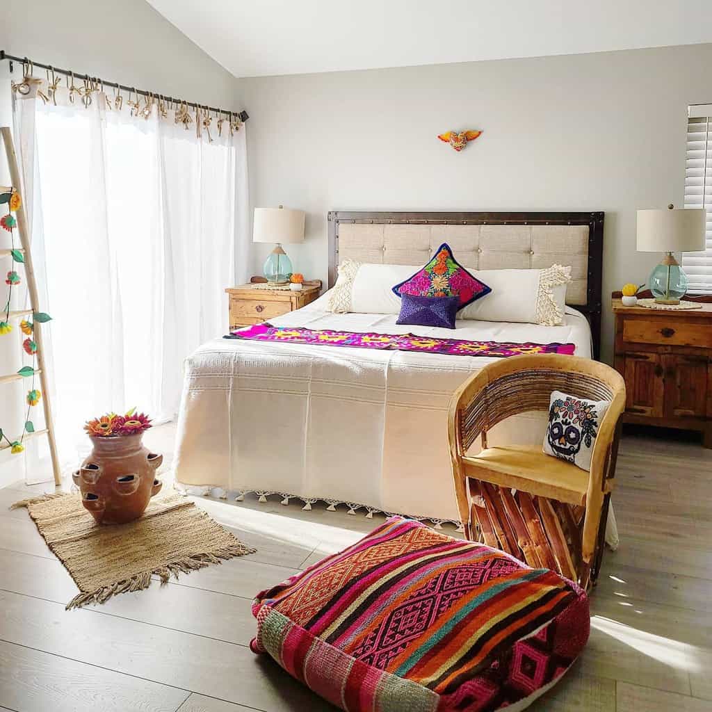 Cozy bedroom with a woven chair, colorful cushions, wooden furniture, a potted plant, and sheer curtains letting in natural light