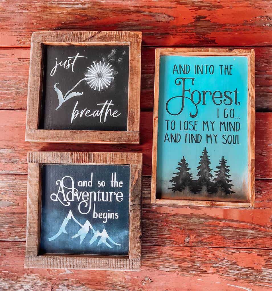 Three framed quotes on a wooden wall: "Just breathe," "And so the adventure begins," "And into the forest I go..."