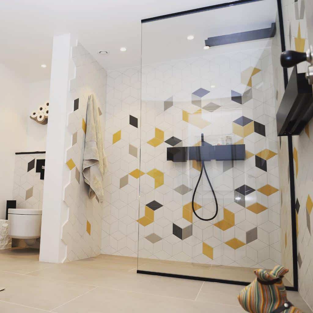 Modern wet room with geometric patterned tiles in yellow, gray, and white, featuring a walk-in shower and minimalist design accents