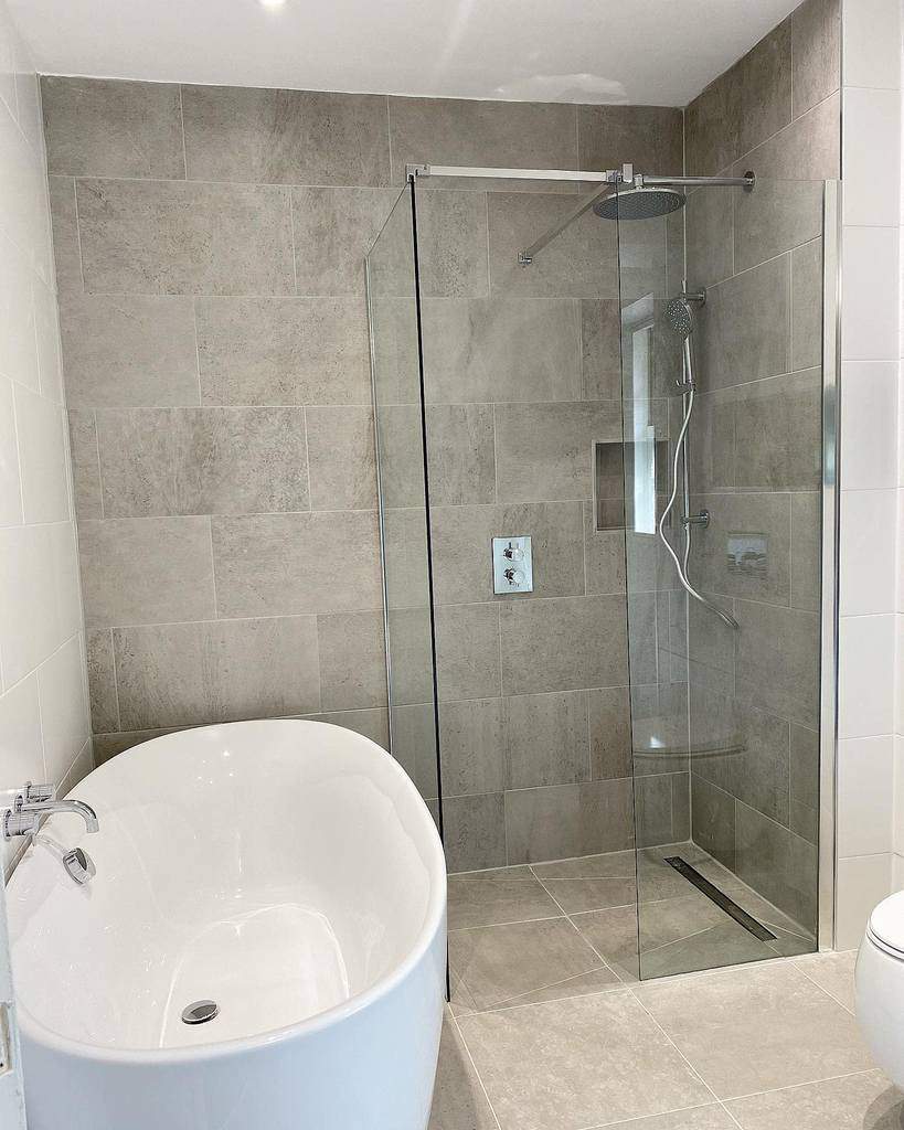 Minimalist wet room with neutral-toned tiles, a frameless glass shower, and a freestanding tub for a sleek and calming spa-like space