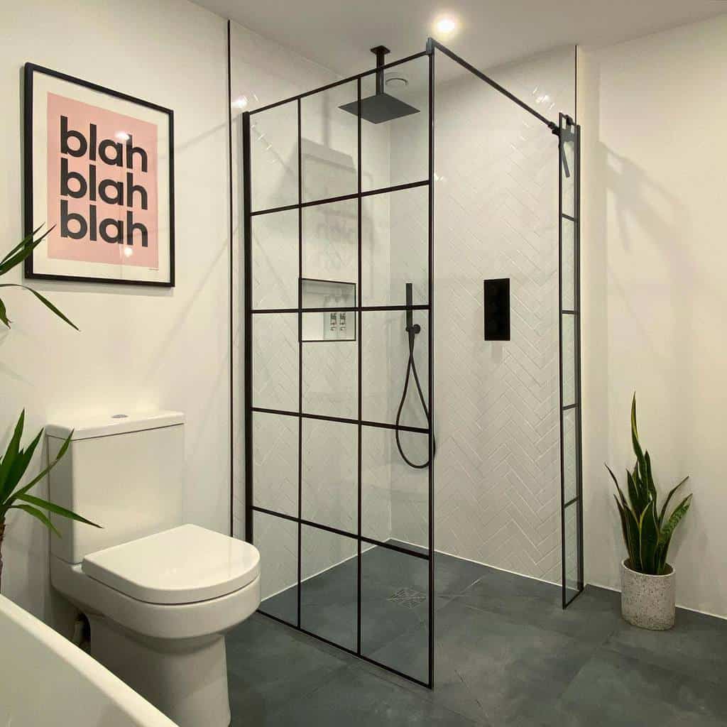 Minimalist wet room with a black-framed glass shower, white herringbone tiles, dark flooring, and modern decor for a bold contrast