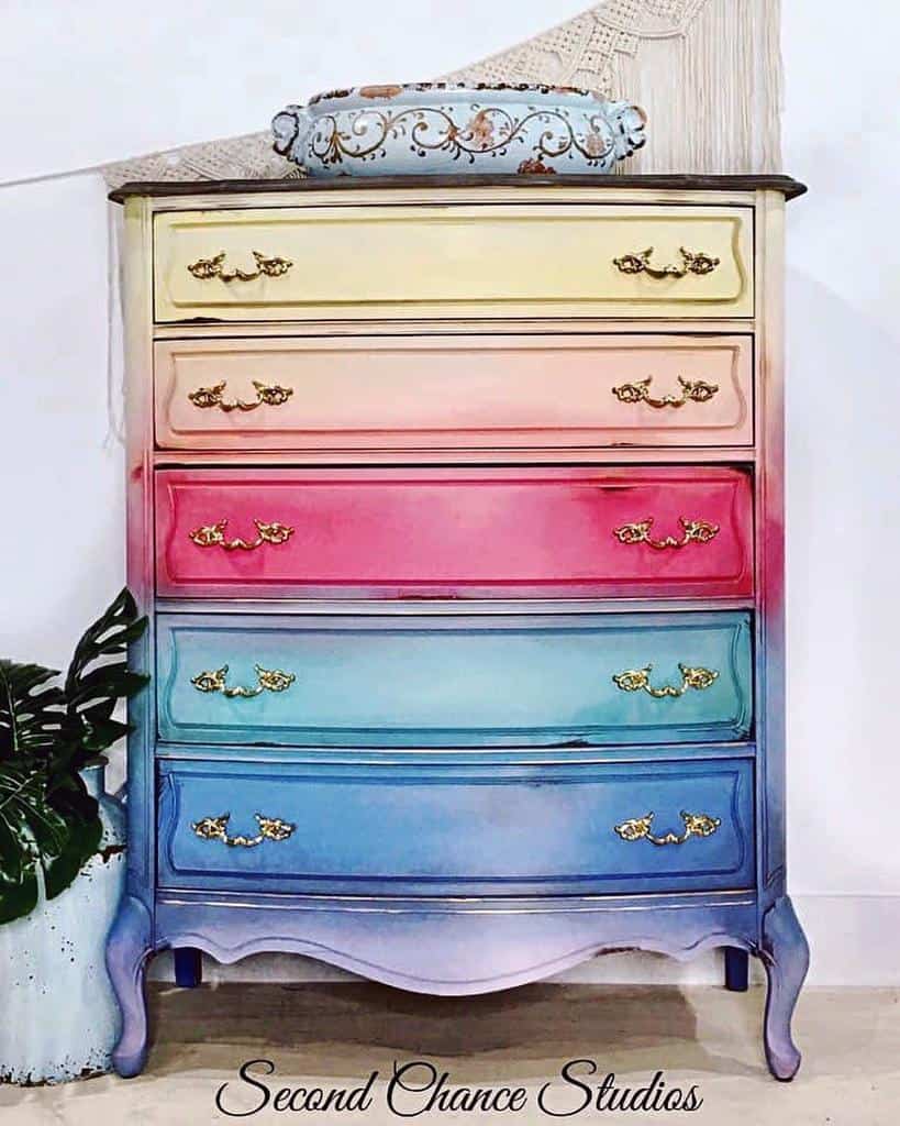 Vibrant ombre chalk-painted dresser with a rainbow gradient from yellow to blue, accented with ornate gold handles for a vintage touch