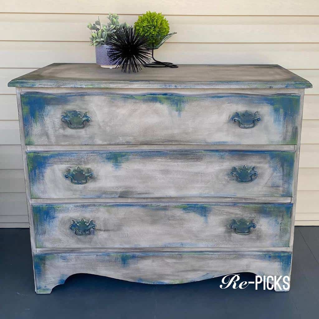 Distressed chalk-painted dresser with a weathered gray finish, hints of blue and green, and vintage-style hardware for a rustic look