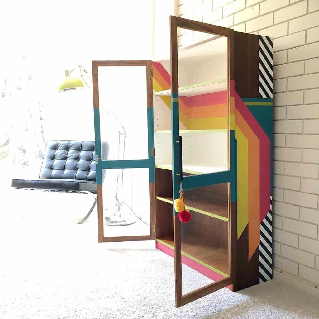 Retro-inspired cabinet with bold rainbow stripes, geometric patterns, and glass doors, blending mid-century and modern eclectic design