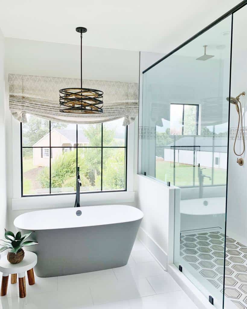 Bright wet room with a freestanding tub, large windows, glass shower enclosure, and geometric tile flooring for a modern farmhouse feel